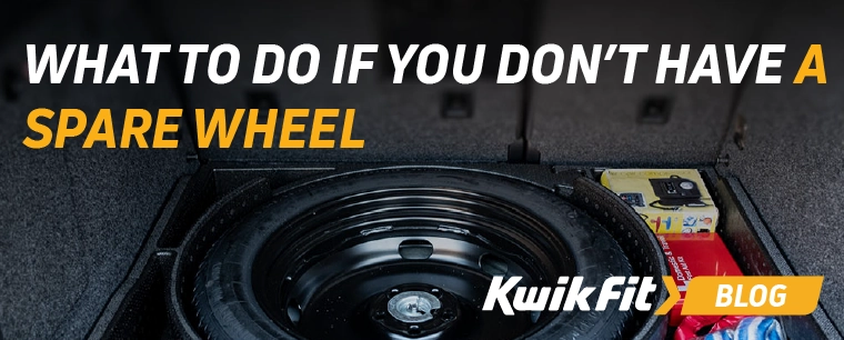 A spare wheel in its well in the trunk of a car, next to a first aid kit and tow rope.